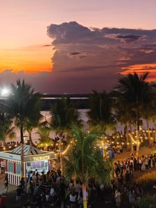 Manila bayfront at sunset with palm trees and crowds